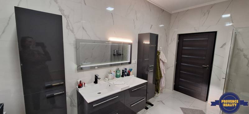 Kúpeľňa v rodinnom dome s moderným umývadlom a skrinkami s vysokým leskom.