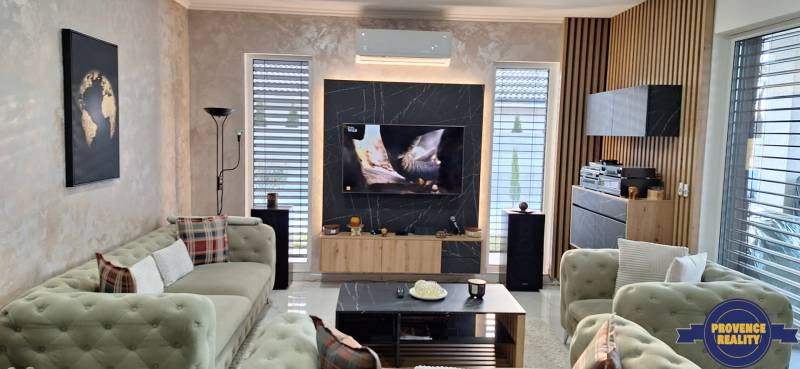 Obývačka v rodinnom dome s pohodlnými pohovkami, TV a dekoratívnou stenou s drevom.