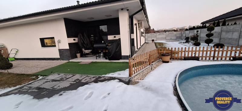 Sneh pokrytá záhrada rodinného domu v Kolárove s bazénom a terasou.