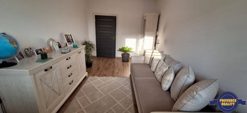 Rodinný dom s podlahou s dreveným dekorom, pohovkou a dekoráciami na bielej komode.