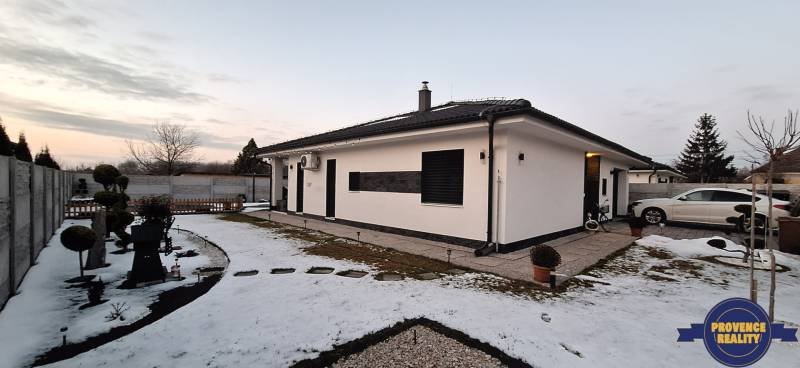 Rodinný dom v Kolárove so zasneženou záhradou a zaparkovaným autom.