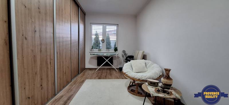 Izba v rodinnom dome s pohovkou, veľkou skriňou a podlahou s dreveným dekorom.