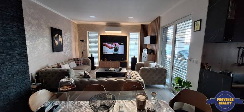 Obývacia izba v rodinnom dome s pohovkou, televízorom a dekoratívnou stenou.