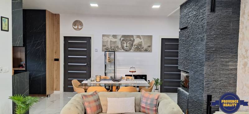 Interiér rodinného domu s tmavými dverami, kamenným obkladom a dekoráciou Budhu.