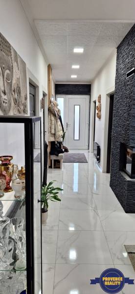 Rodinný dom s mramorovou podlahou, dekoratívnym umením a presklenou vitrínou na chodbe.