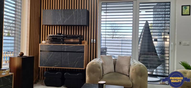 Obývacia izba rodinného domu s mramorovým dekorom, drevenými lamelami a pohodlným kreslom.